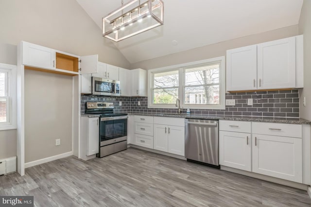 kitchen featuring light wood-type flooring, a sink, stainless steel appliances, white cabinets, and lofted ceiling