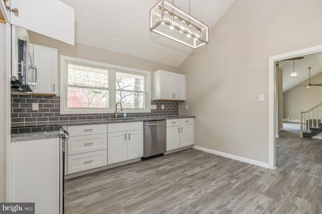 kitchen featuring tasteful backsplash, vaulted ceiling, stainless steel dishwasher, white cabinetry, and a sink