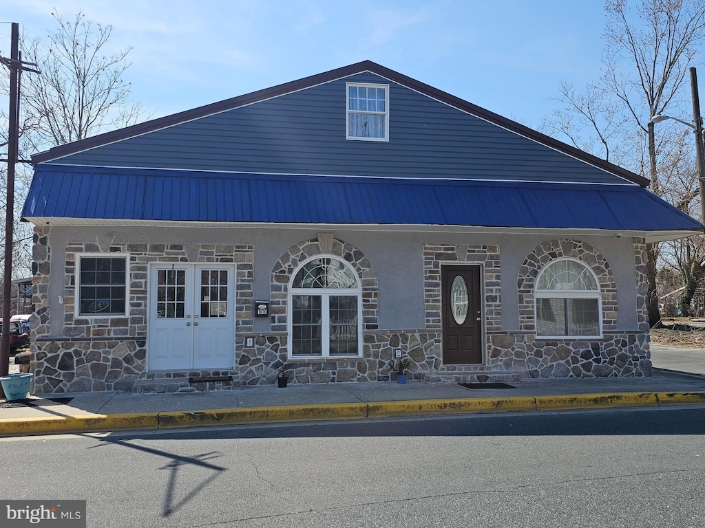 view of front of property with stone siding, stucco siding, and metal roof