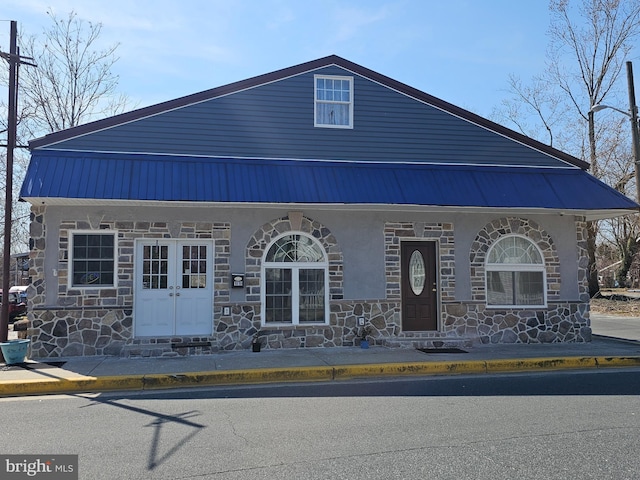 view of front of property with stone siding, stucco siding, and metal roof