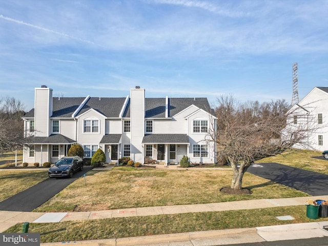 view of front of property featuring driveway, a chimney, and a front yard