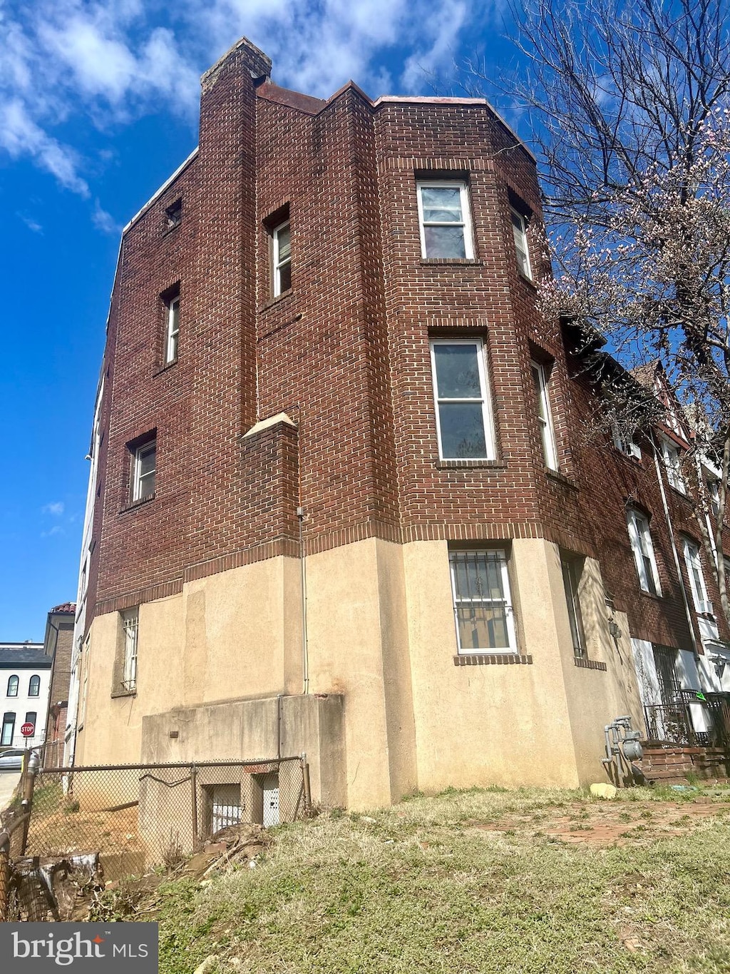 view of side of home with brick siding, stucco siding, and fence