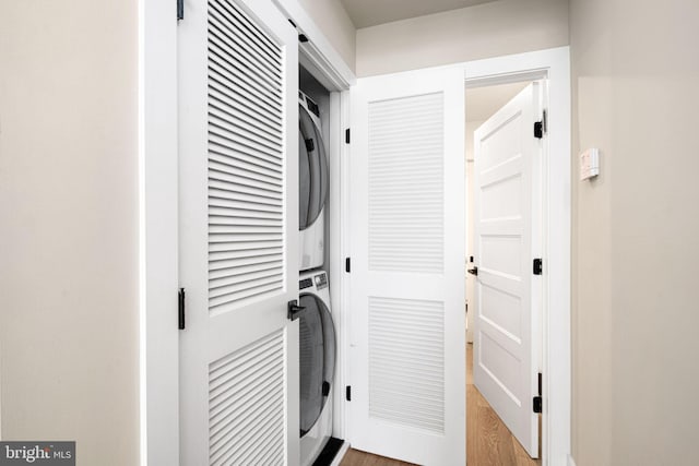 washroom with laundry area, stacked washer / dryer, and wood finished floors