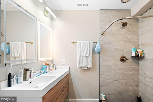 full bathroom featuring double vanity, visible vents, tiled shower, and a sink