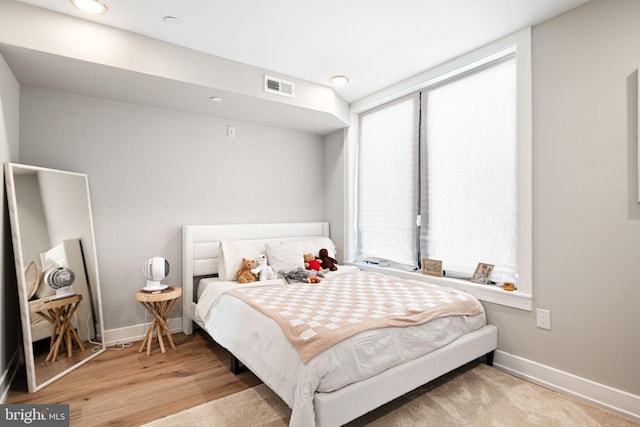 bedroom featuring visible vents, baseboards, and wood finished floors