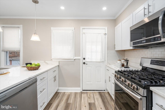 kitchen with stainless steel appliances, backsplash, white cabinets, and crown molding