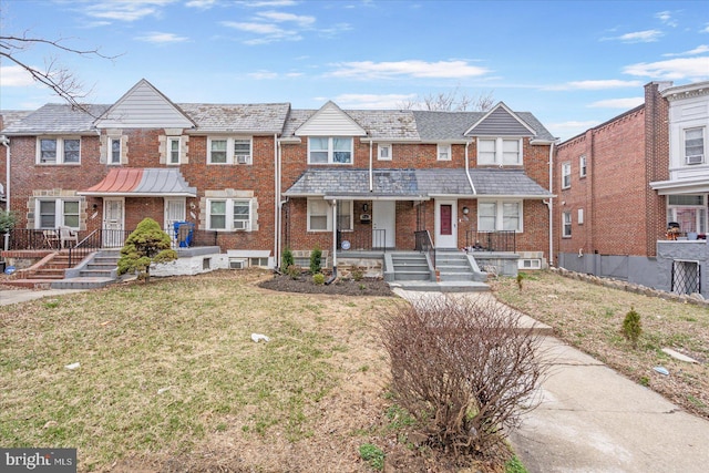 view of property featuring brick siding, a high end roof, a front lawn, and fence