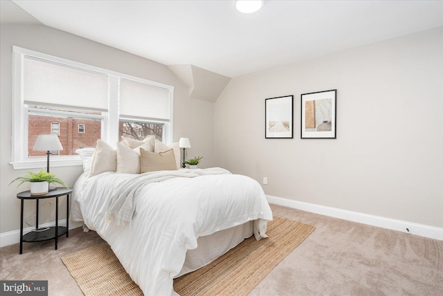 bedroom featuring vaulted ceiling, light colored carpet, and baseboards