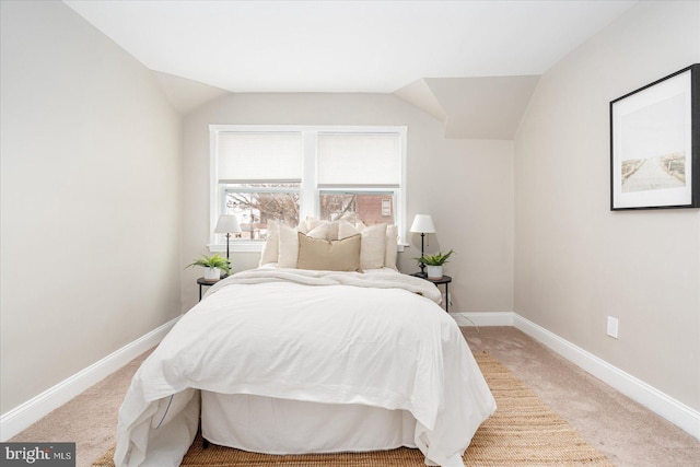 bedroom featuring vaulted ceiling, light colored carpet, and baseboards