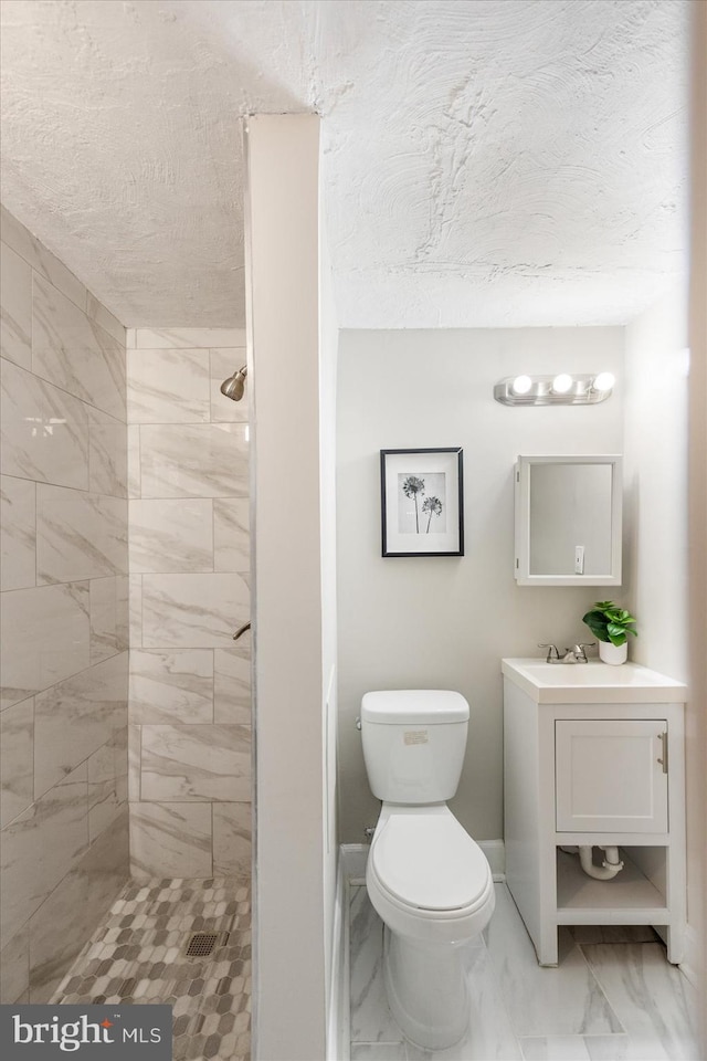 full bath with a textured ceiling, toilet, marble finish floor, and tiled shower