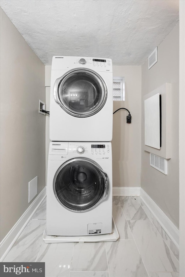 laundry room with laundry area, marble finish floor, stacked washing maching and dryer, and baseboards