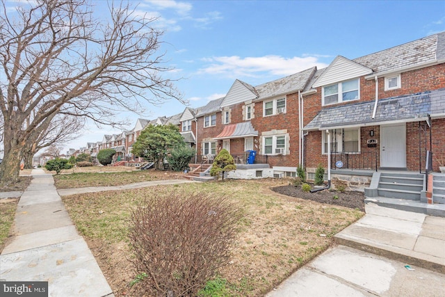 townhome / multi-family property featuring a high end roof, a residential view, and brick siding