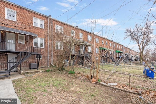 exterior space with brick siding, stairs, and fence