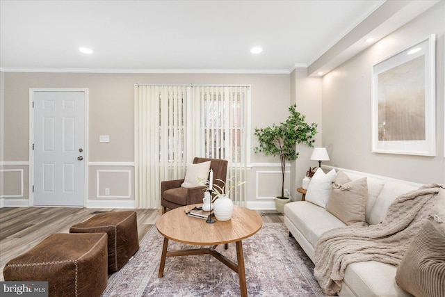 living room with wainscoting, wood finished floors, crown molding, and a decorative wall