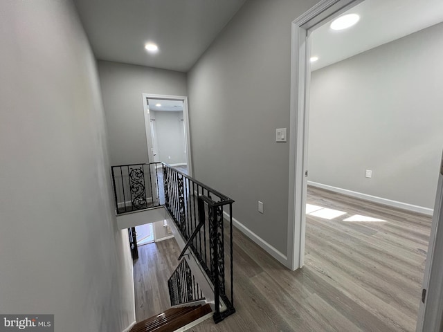 stairs with recessed lighting, wood finished floors, and baseboards