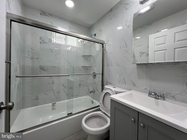 bathroom with toilet, combined bath / shower with glass door, tile walls, decorative backsplash, and vanity