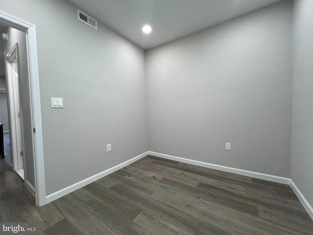 empty room featuring visible vents, baseboards, and dark wood-style flooring