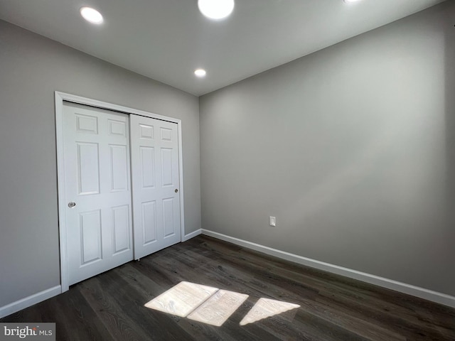 unfurnished bedroom with dark wood finished floors, recessed lighting, a closet, and baseboards