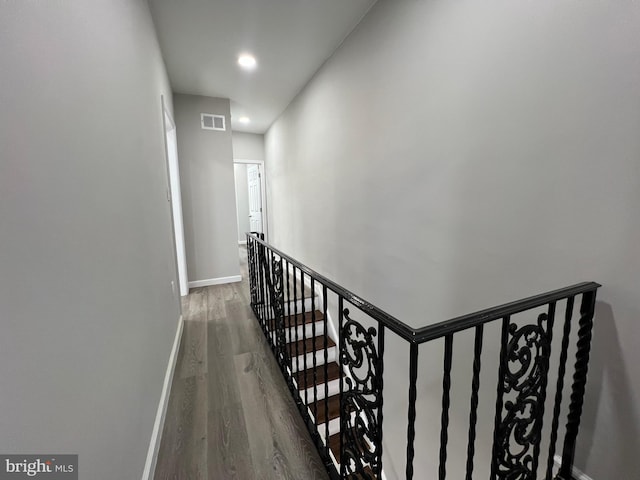 hall with wood finished floors, visible vents, baseboards, recessed lighting, and an upstairs landing