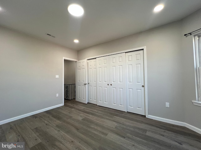 unfurnished bedroom with visible vents, dark wood-type flooring, baseboards, recessed lighting, and a closet