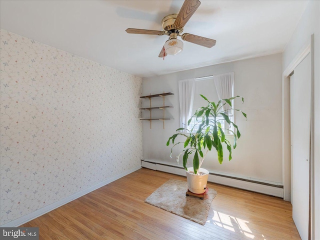 interior space with wallpapered walls, a ceiling fan, baseboards, and wood finished floors