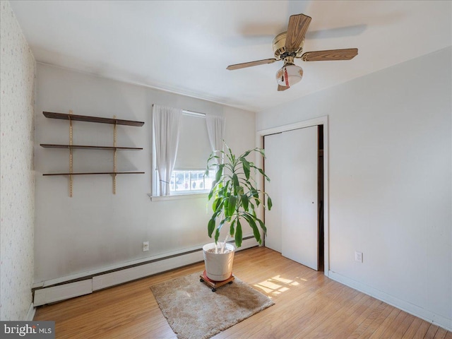 interior space with baseboard heating, ceiling fan, and wood finished floors