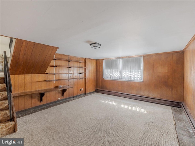 carpeted spare room featuring wooden walls and baseboard heating