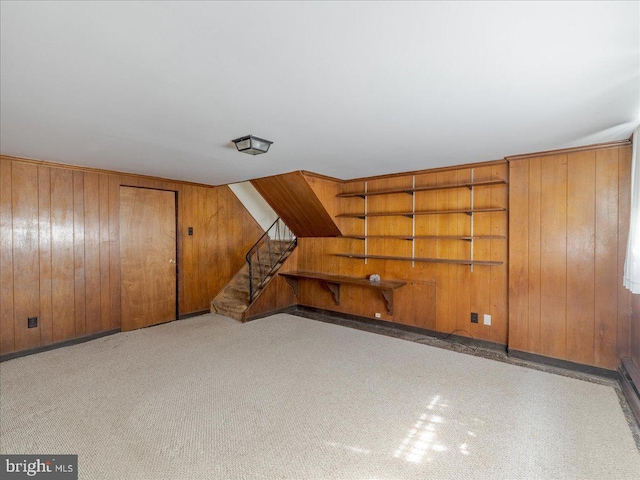 additional living space with carpet flooring, wood walls, and stairs