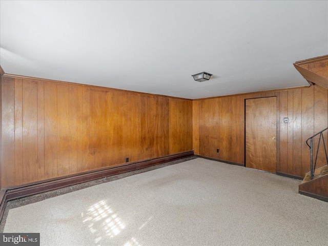 carpeted empty room featuring wooden walls