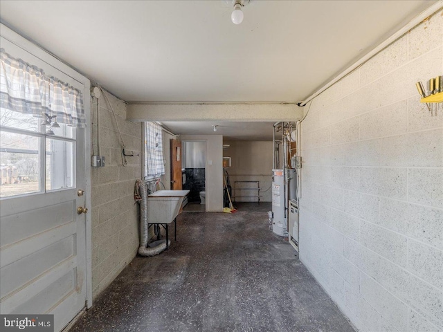 interior space with gas water heater, concrete floors, and concrete block wall