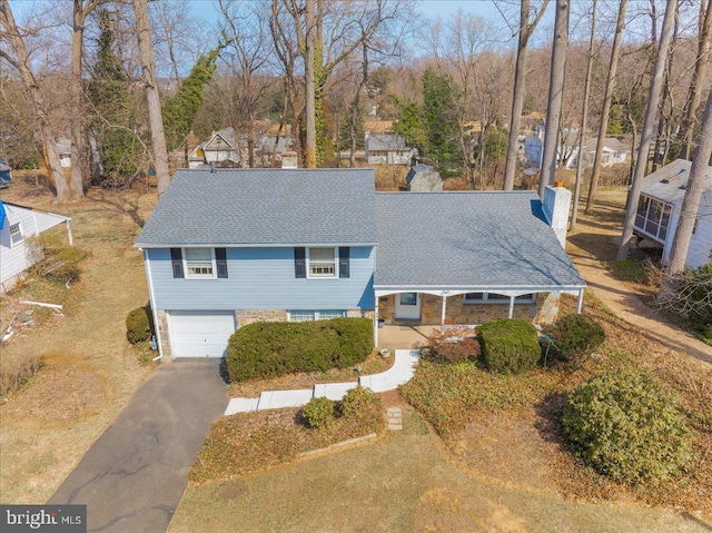 view of front of home with a chimney, driveway, an attached garage, and a shingled roof