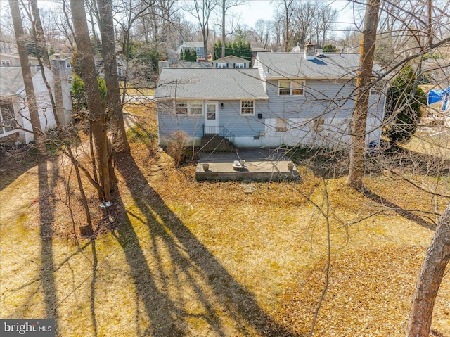 rear view of house featuring entry steps, roof with shingles, and a chimney