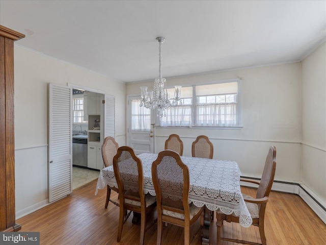 dining space featuring light wood finished floors, a healthy amount of sunlight, crown molding, and an inviting chandelier