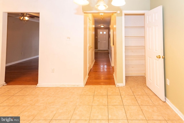 corridor featuring light tile patterned floors and baseboards