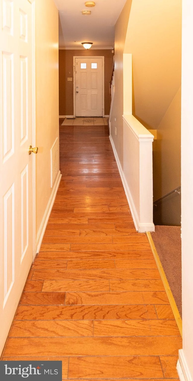 hallway featuring light wood-type flooring, baseboards, and visible vents