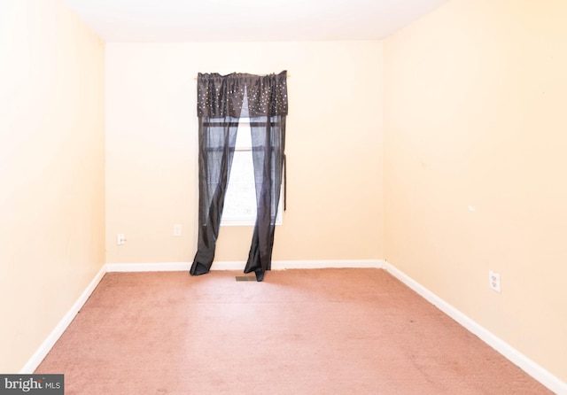 empty room featuring light colored carpet and baseboards