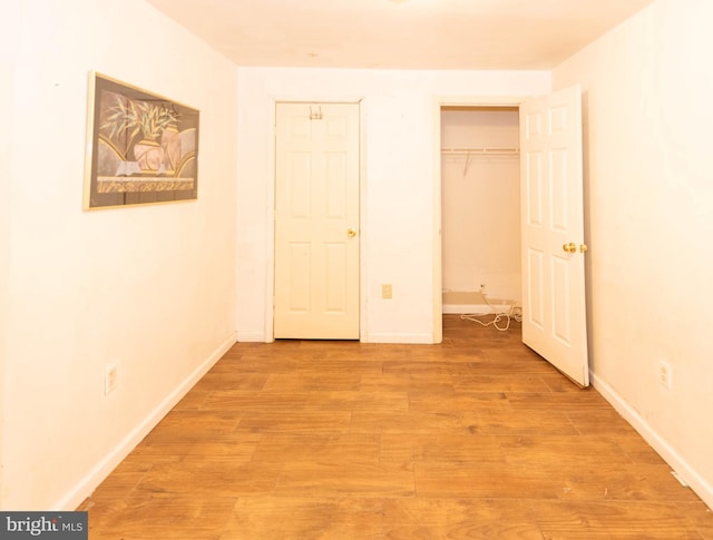 unfurnished bedroom with a closet, light wood-style flooring, and baseboards