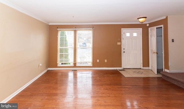 entryway with crown molding, light wood-type flooring, and baseboards