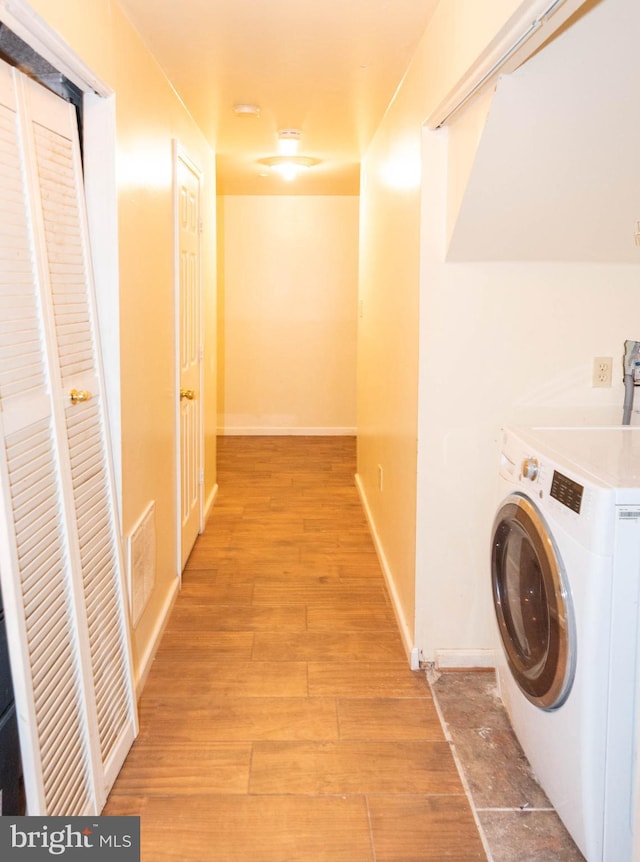 clothes washing area featuring baseboards, visible vents, washer / dryer, laundry area, and light wood-style floors