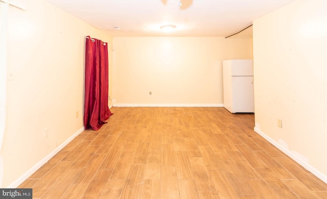 unfurnished room featuring baseboards and light wood-style floors