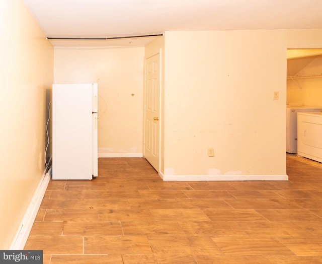 unfurnished room featuring light wood finished floors, washer / dryer, and baseboards