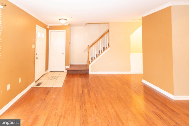 foyer entrance featuring visible vents, baseboards, stairway, ornamental molding, and wood finished floors