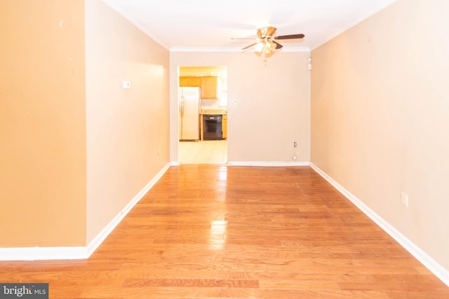 spare room featuring crown molding, baseboards, and light wood finished floors