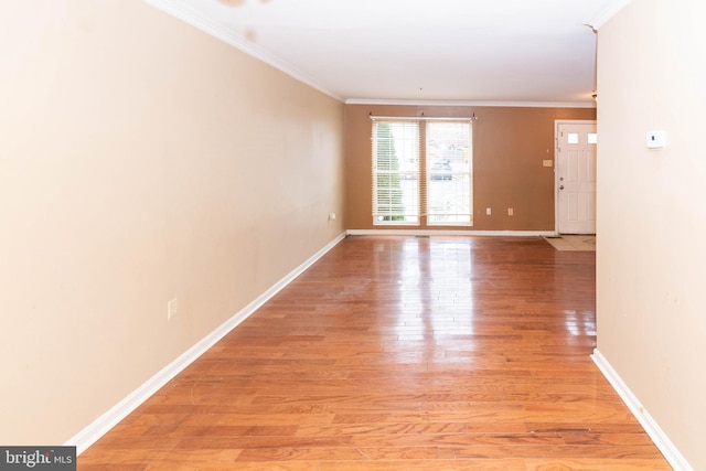 spare room featuring light wood-style flooring, crown molding, and baseboards