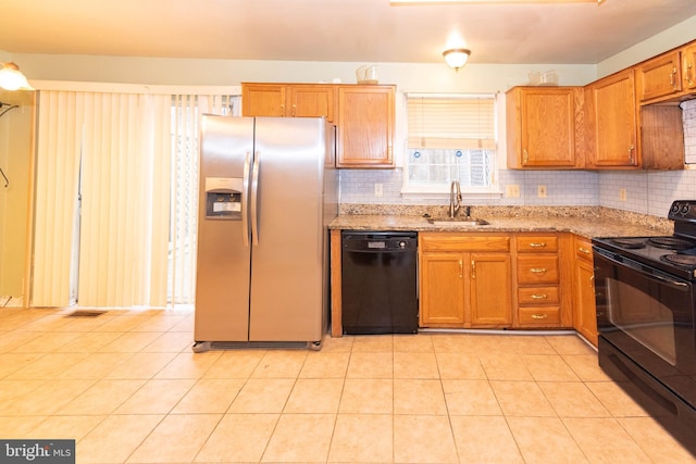 kitchen with decorative backsplash, light stone countertops, black appliances, and a sink