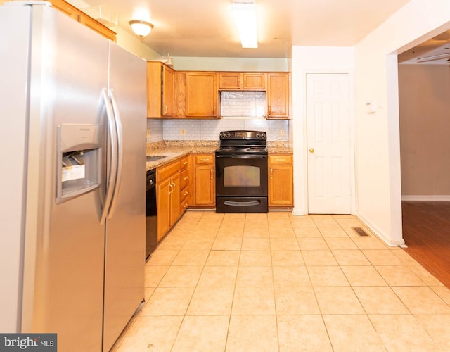 kitchen featuring light stone countertops, baseboards, light tile patterned flooring, decorative backsplash, and black appliances