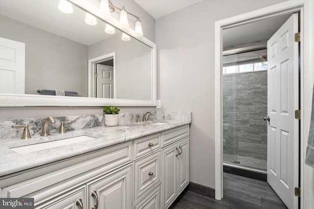 full bathroom with double vanity, a stall shower, wood finished floors, and a sink