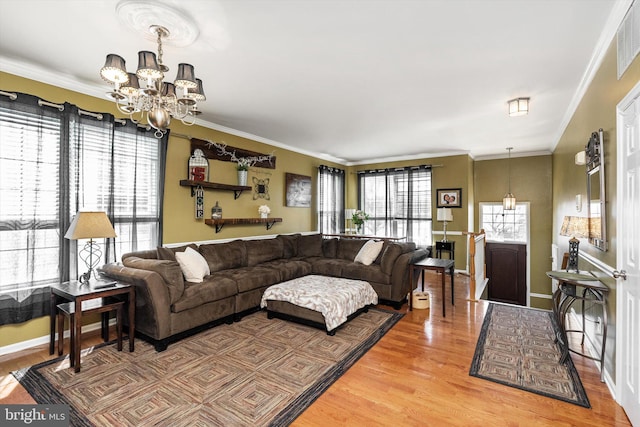 living room with a wealth of natural light, a notable chandelier, crown molding, and light wood-style floors