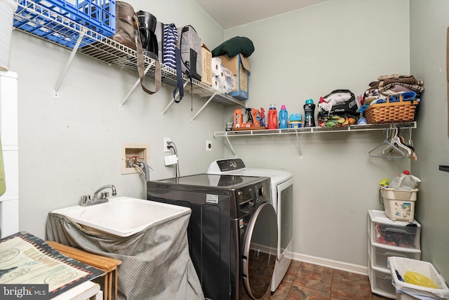 laundry room featuring laundry area, separate washer and dryer, baseboards, and a sink