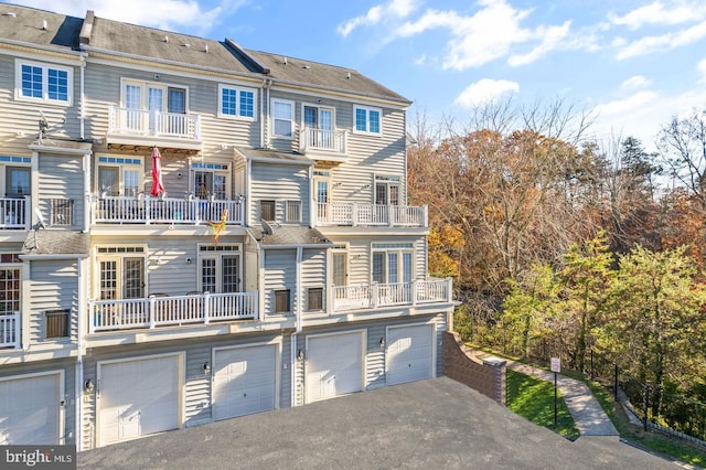 rear view of property featuring driveway and an attached garage